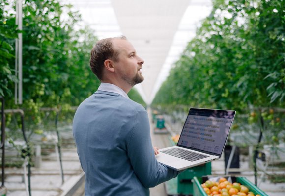 Grower with Priva One in greenhouse checking climate, water, energy via intuitive dashboards