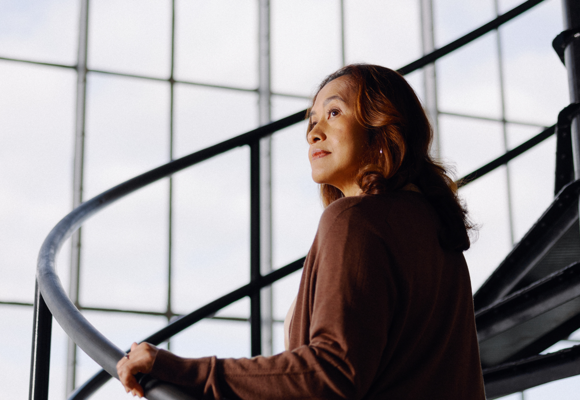 Person walking up spiral staircase in modern industrial building with large grid windows and natural light